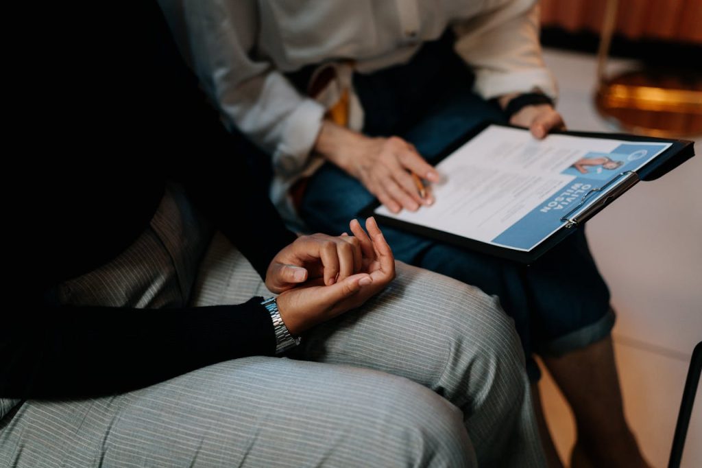 person-in-white-long-sleeve-shirt-holding-a-clipboard-with-resume-5989933 Two professionals reviewing a resume in an office setting, focused on teamwork.